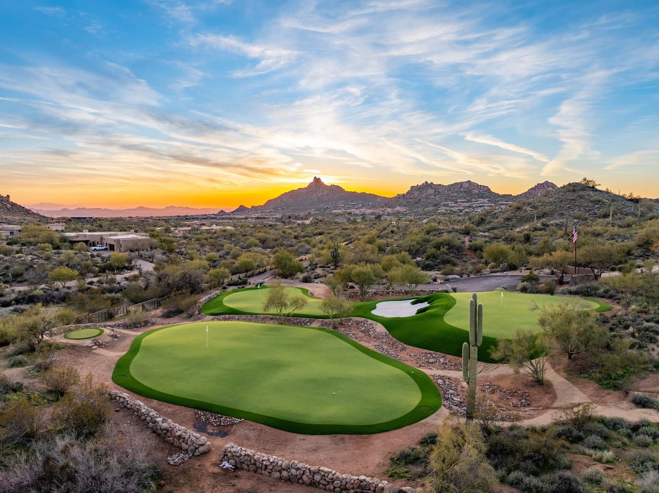The private greens with the flag at golden hour beneath Pinnacle Peak