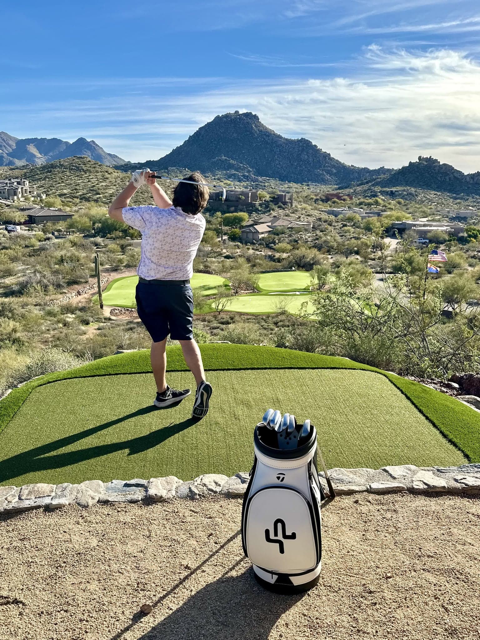 A guest taking a swing on the private green with Pinnacle Peak behind