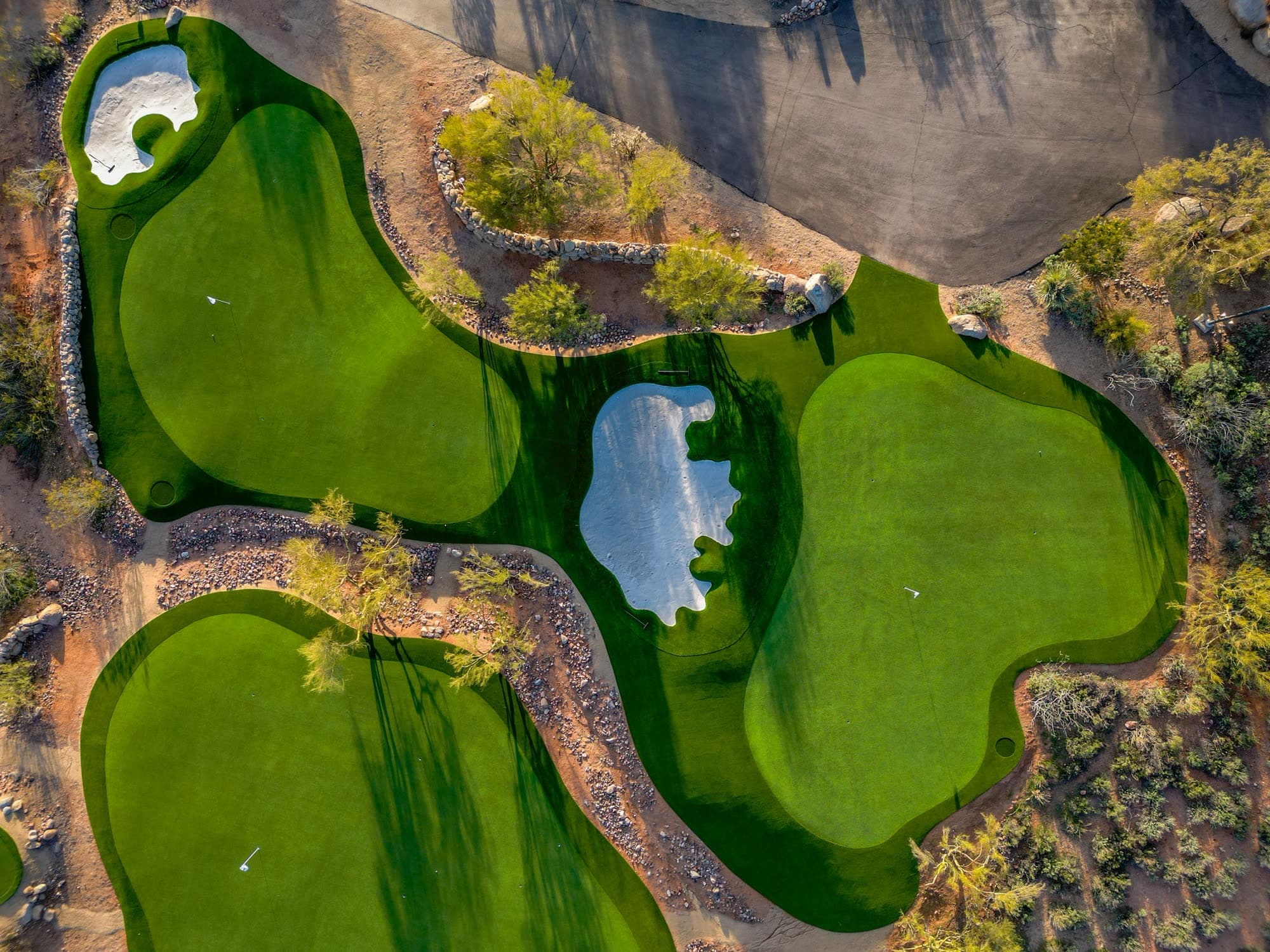 Straight-down overhead view of the practice complex, its bunkers reading as pale abstract shapes