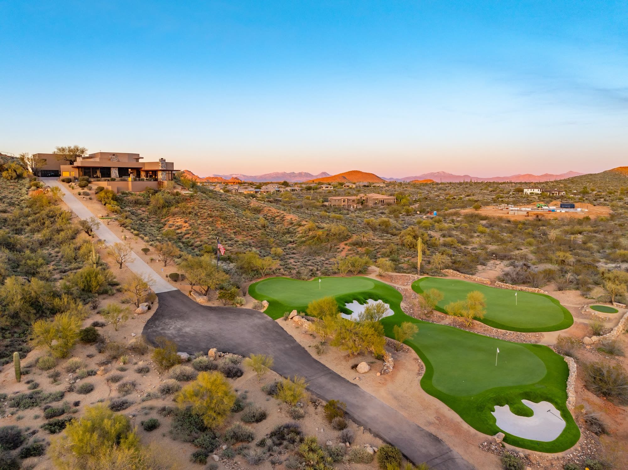 The estate above its greens as alpenglow turns the North Scottsdale mountains pink